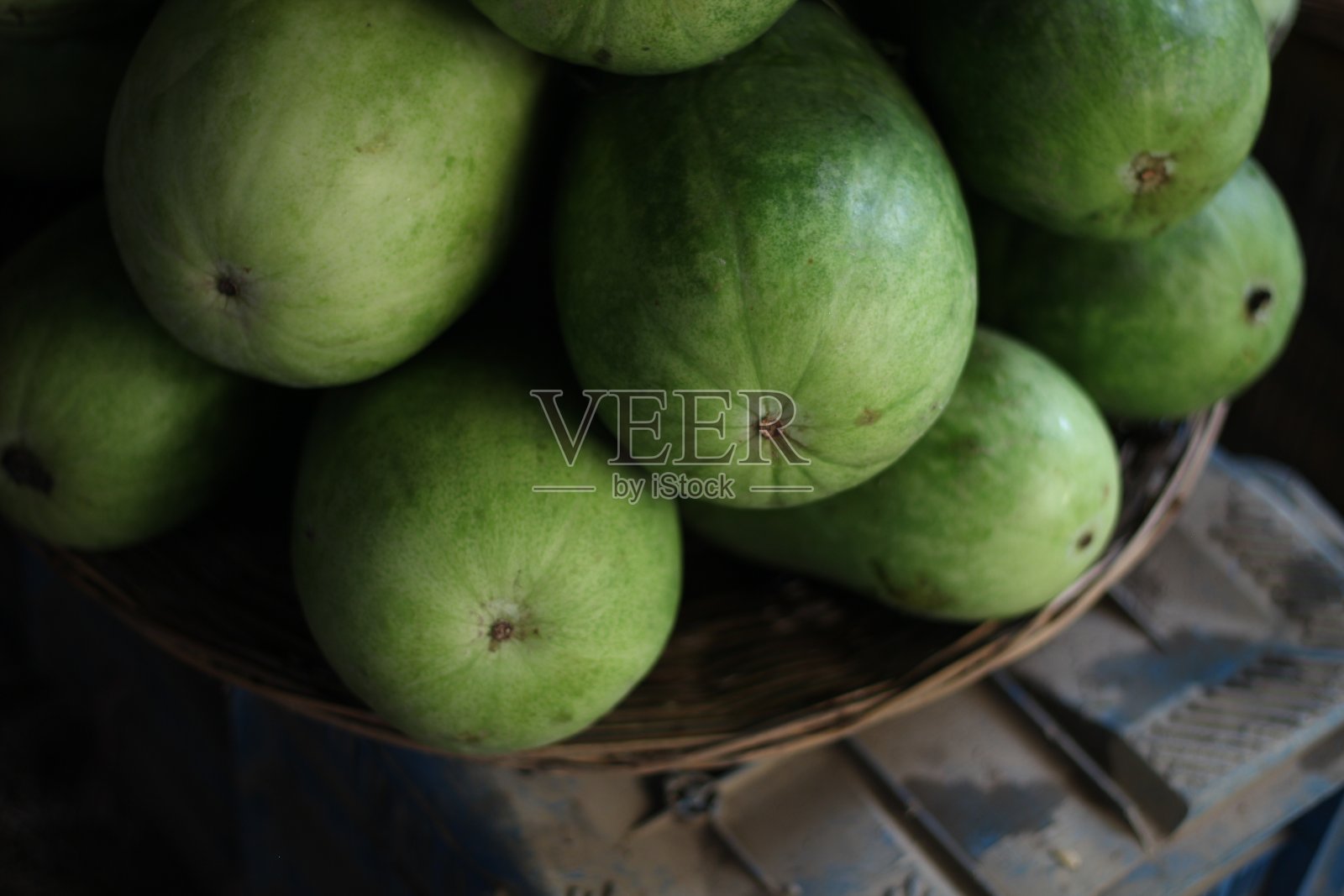 市场里的一堆南瓜，放在一个竹笼里。照片摄影图片