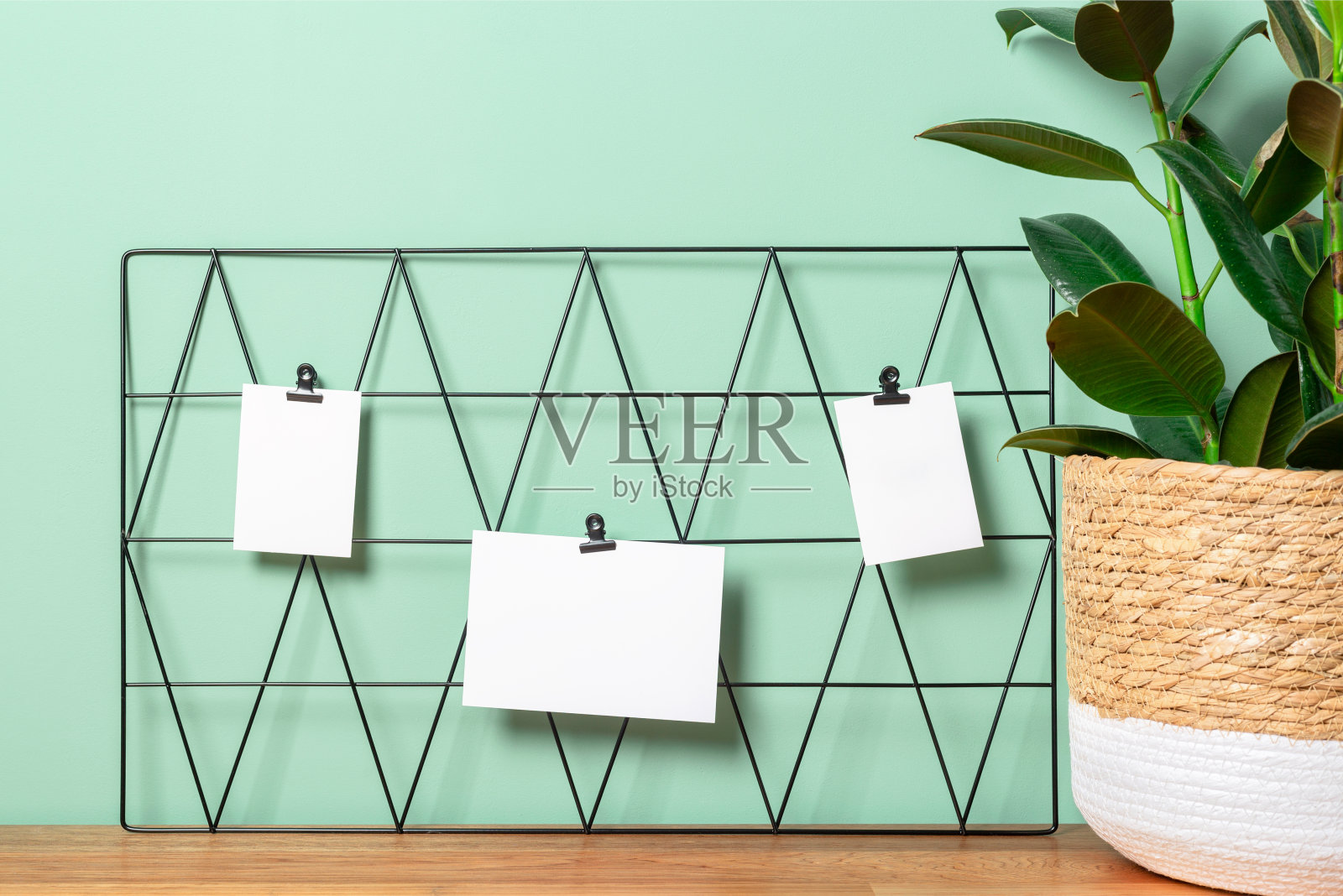 在一个自由职业的工作场所，黑色的情绪板与明信片和提醒模型对着绿色的墙与一个花盆。照片摄影图片