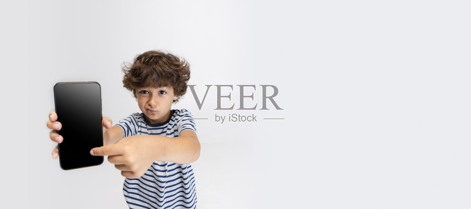 海报上是一个学龄前的小男孩在白色的工作室背景下摆出孤立的姿势。照片摄影图片