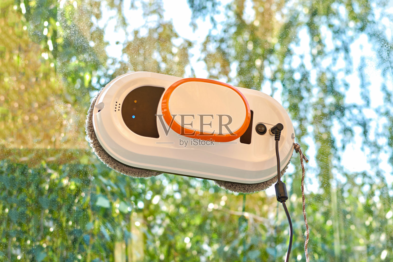 清洁玻璃的机器人。一个机器人真空吸尘器在擦脏窗户。清洁玻璃窗的家庭机器人助手。照片摄影图片