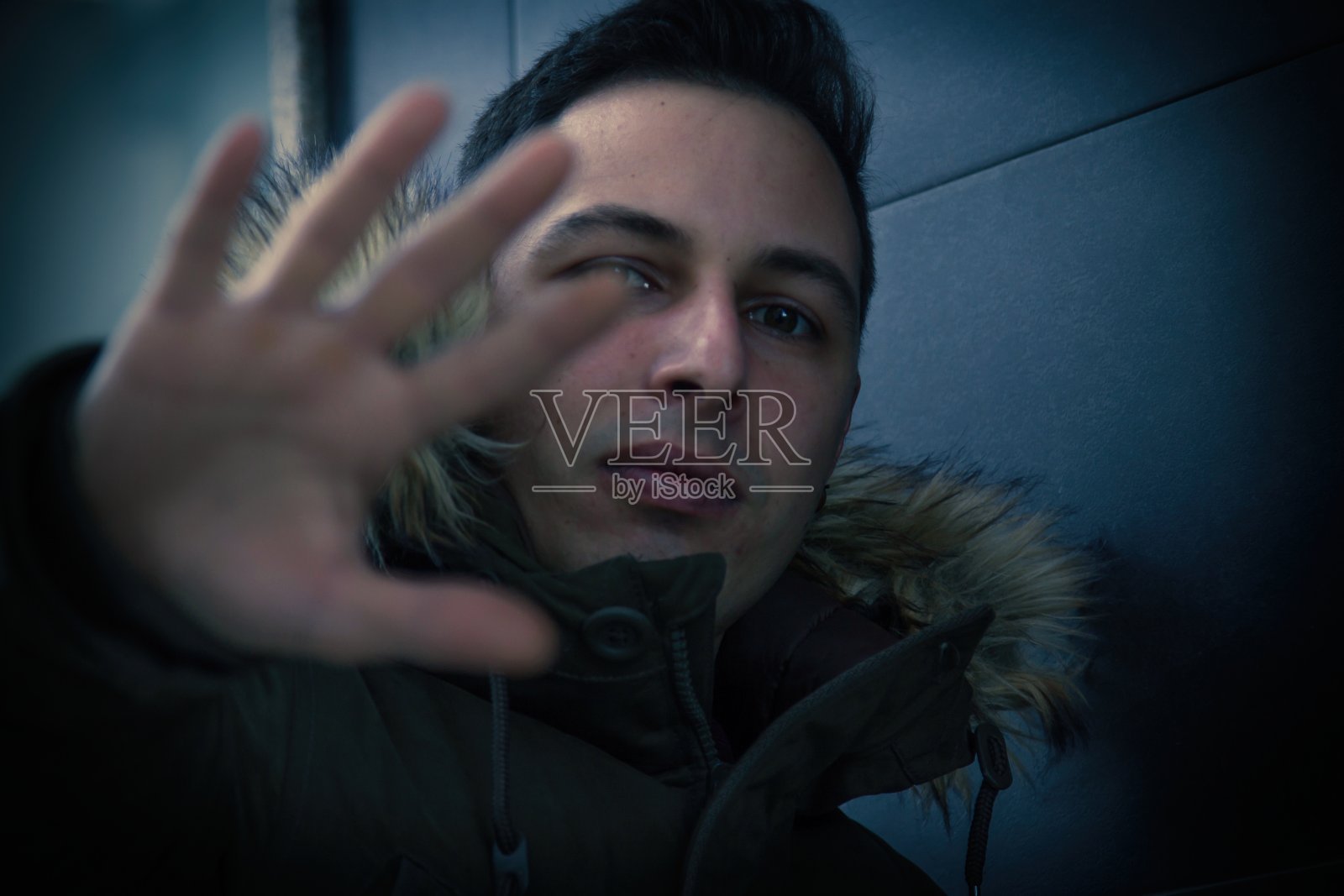 年轻男子的肖像与风帽与严肃的表情掩盖镜头照片摄影图片