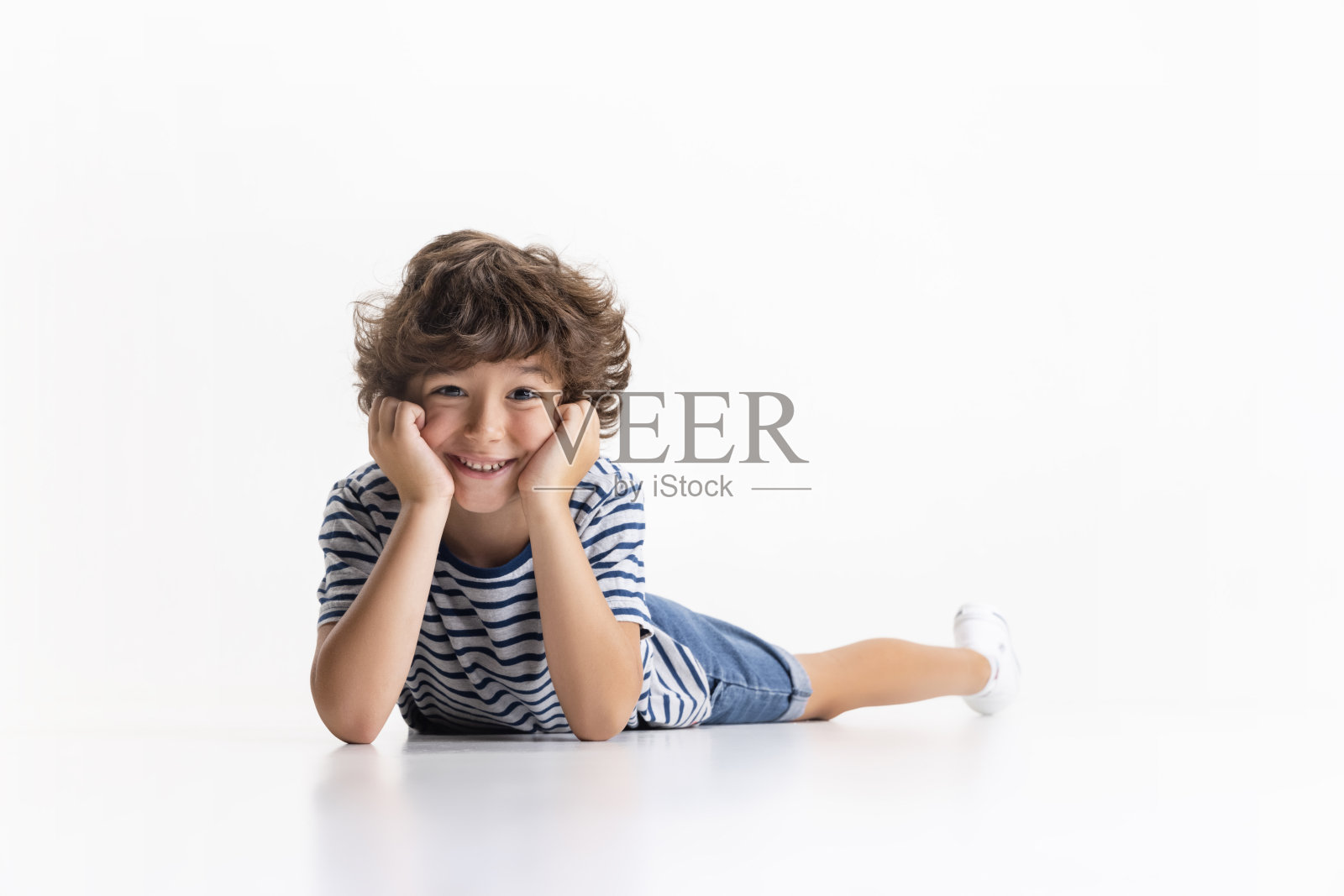一个学龄前的小男孩在白色的工作室背景下摆出孤立的姿势。照片摄影图片