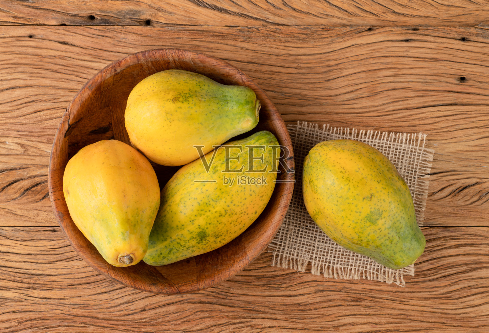 木桌上的碗里放着木瓜照片摄影图片