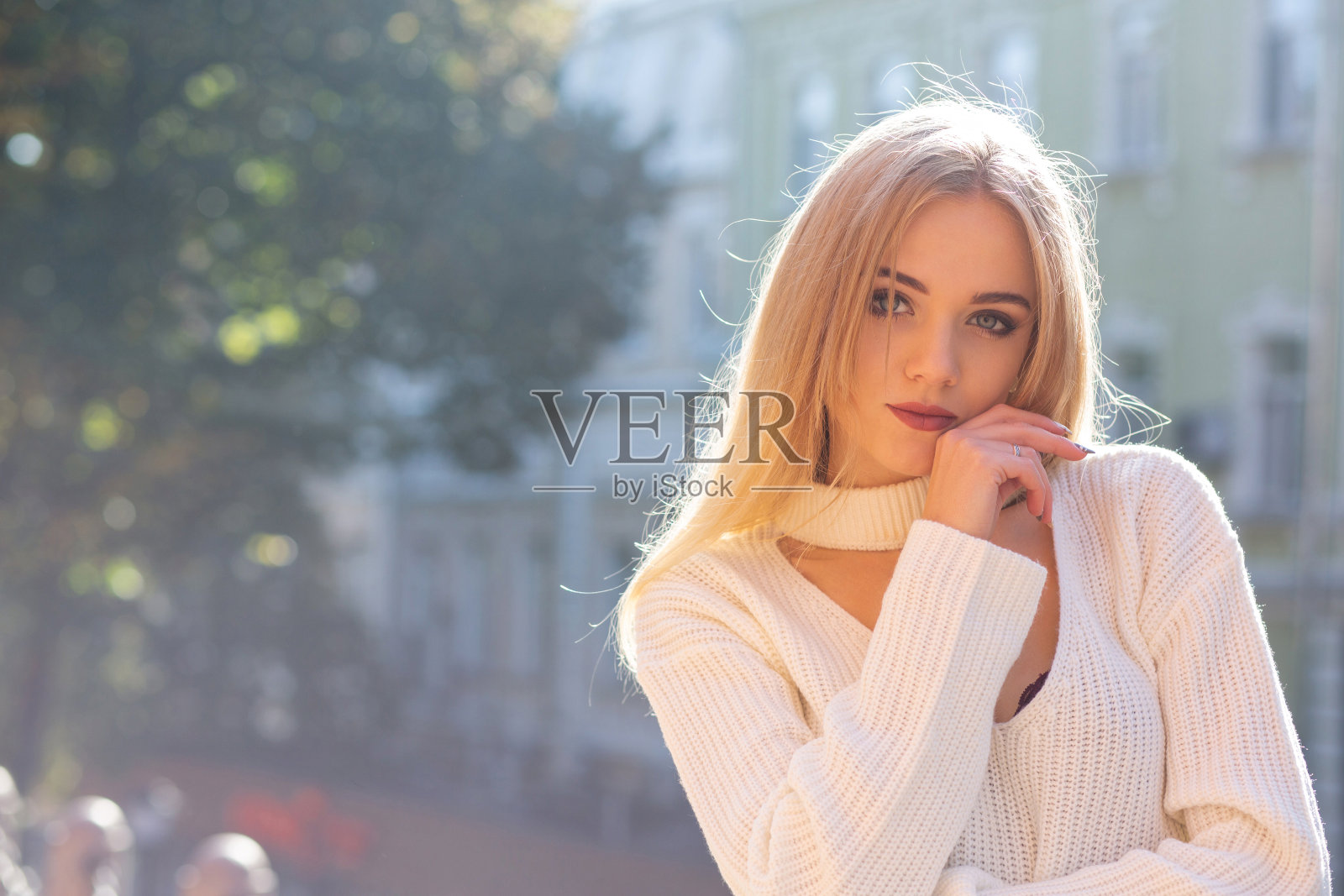 户外肖像迷人的模特穿着时尚的服装摆姿势在街道与自然的阳光。空的空间照片摄影图片