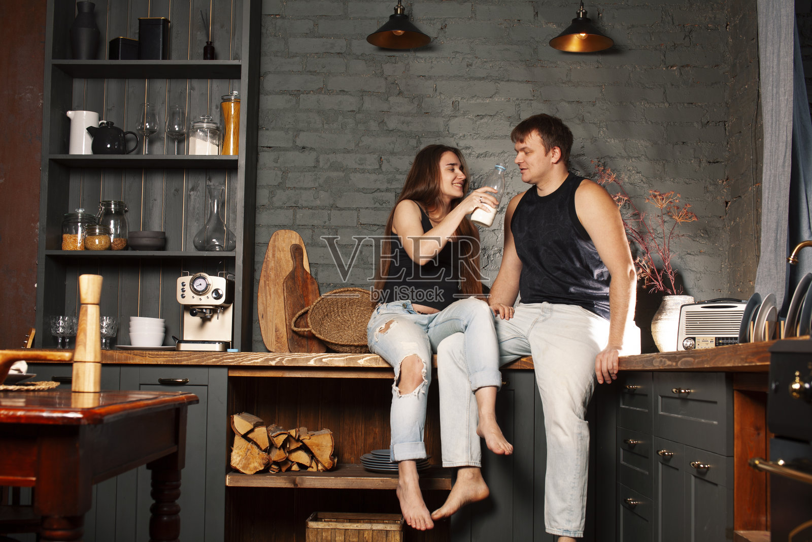 年轻的白种夫妇一起在厨房里玩，女人怀孕，喝牛奶，生活方式的概念照片摄影图片