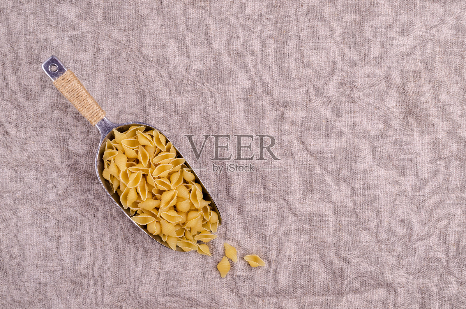 用金属勺舀干意大利面壳照片摄影图片