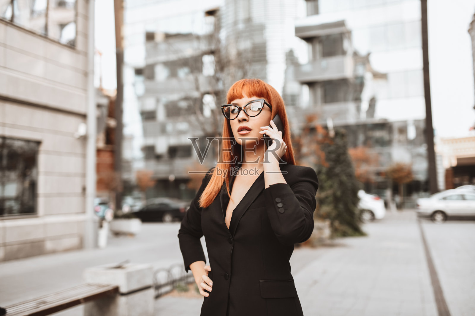 优雅的女商人一边走在市中心一边用智能手机聊天照片摄影图片