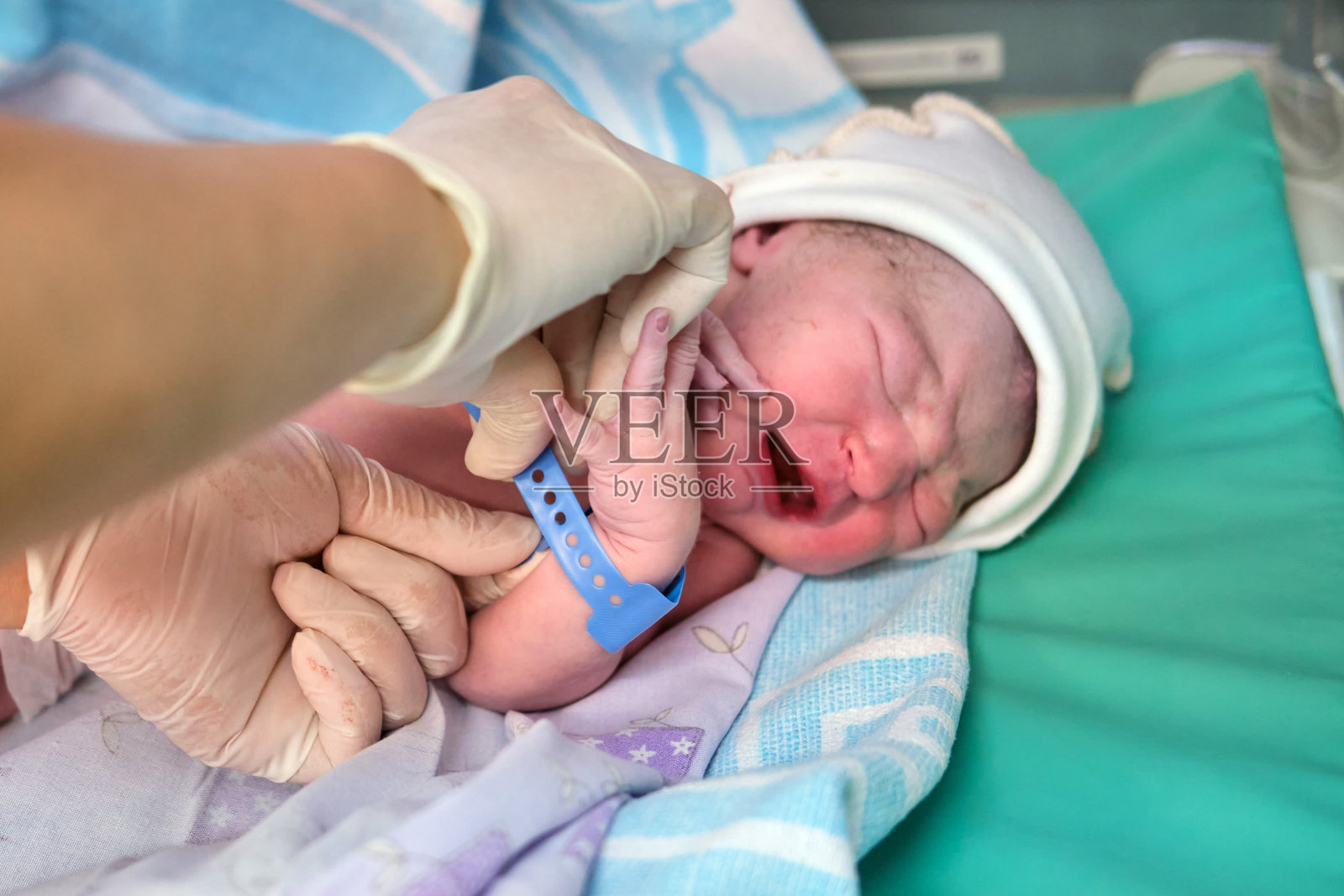 刚出生的婴儿在分娩后立即由医生给其戴上手镯照片摄影图片