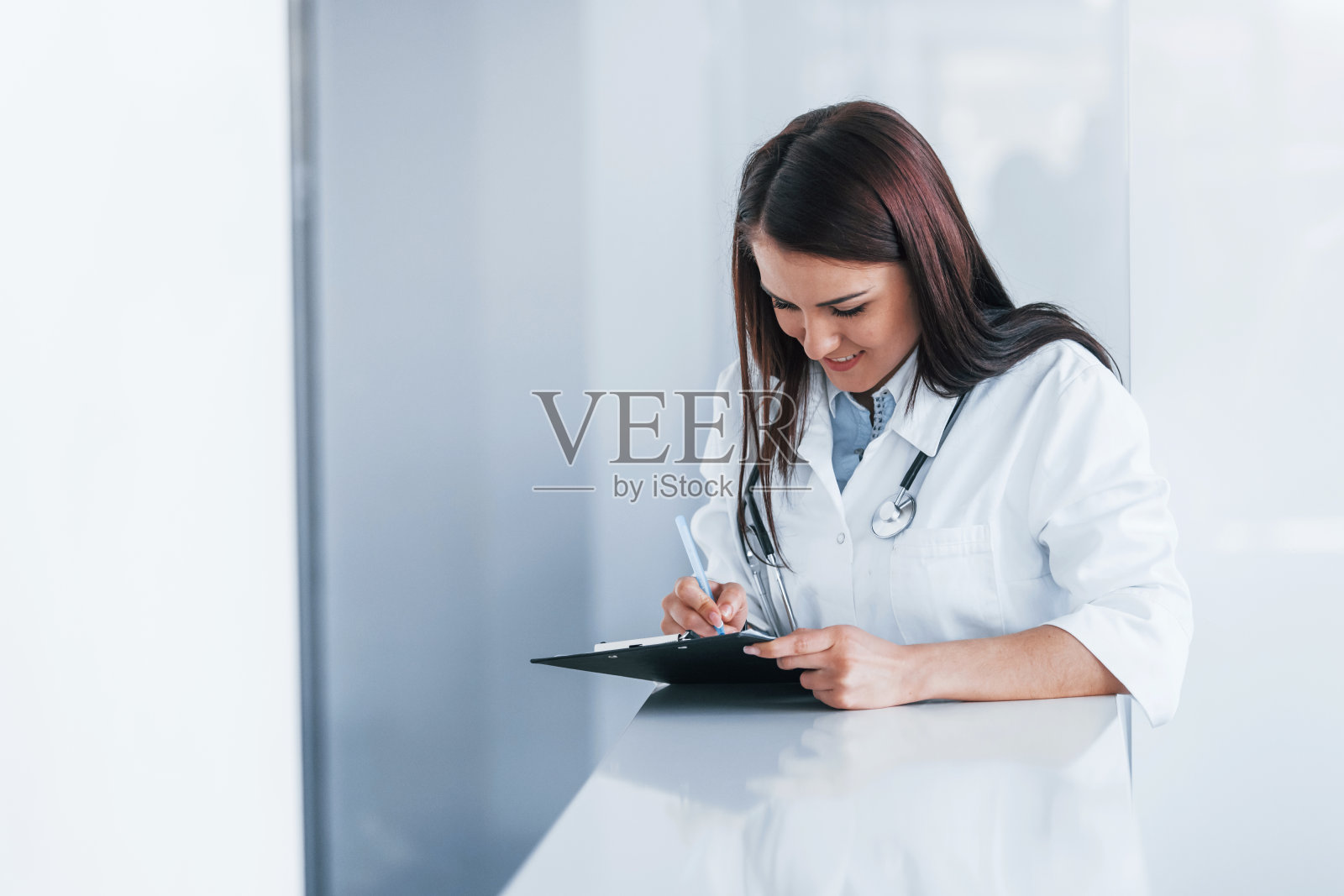 用记事本。现代临床室内年轻护士。医疗保健的概念照片摄影图片