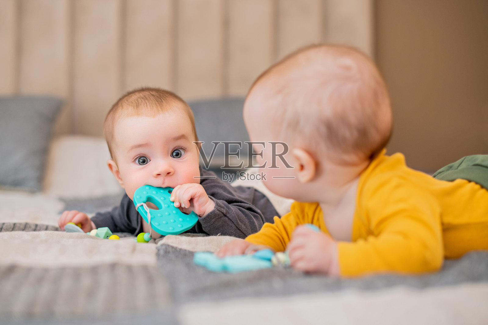 双胞胎宝宝躺在沙发上，咬着牙。照片摄影图片