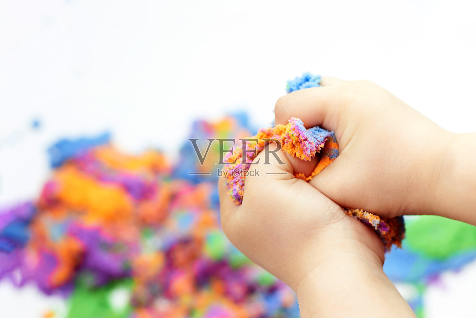 男孩的手正在挤压明亮的动态沙子。照片摄影图片