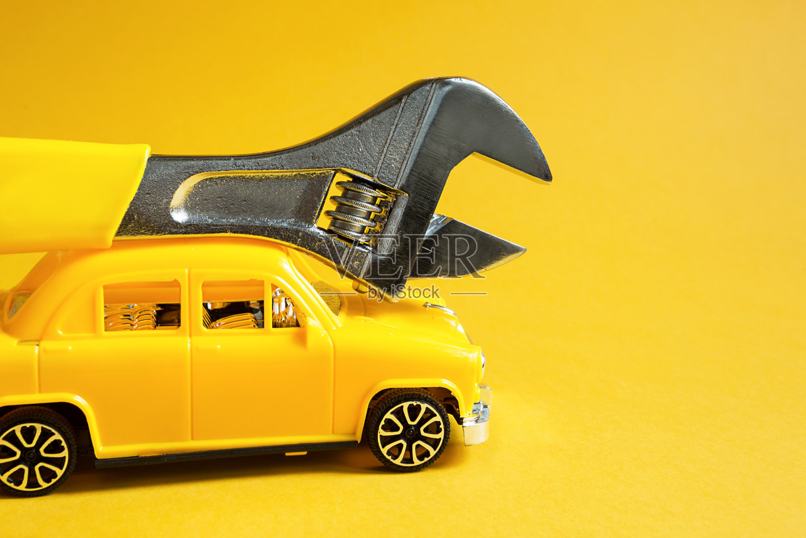 汽车维修和设备及汽车的维修，紧急离境的师傅要杜绝破损，做好给排水工作，施工。修理服务车用可调万能键在黄色背景上。照片摄影图片