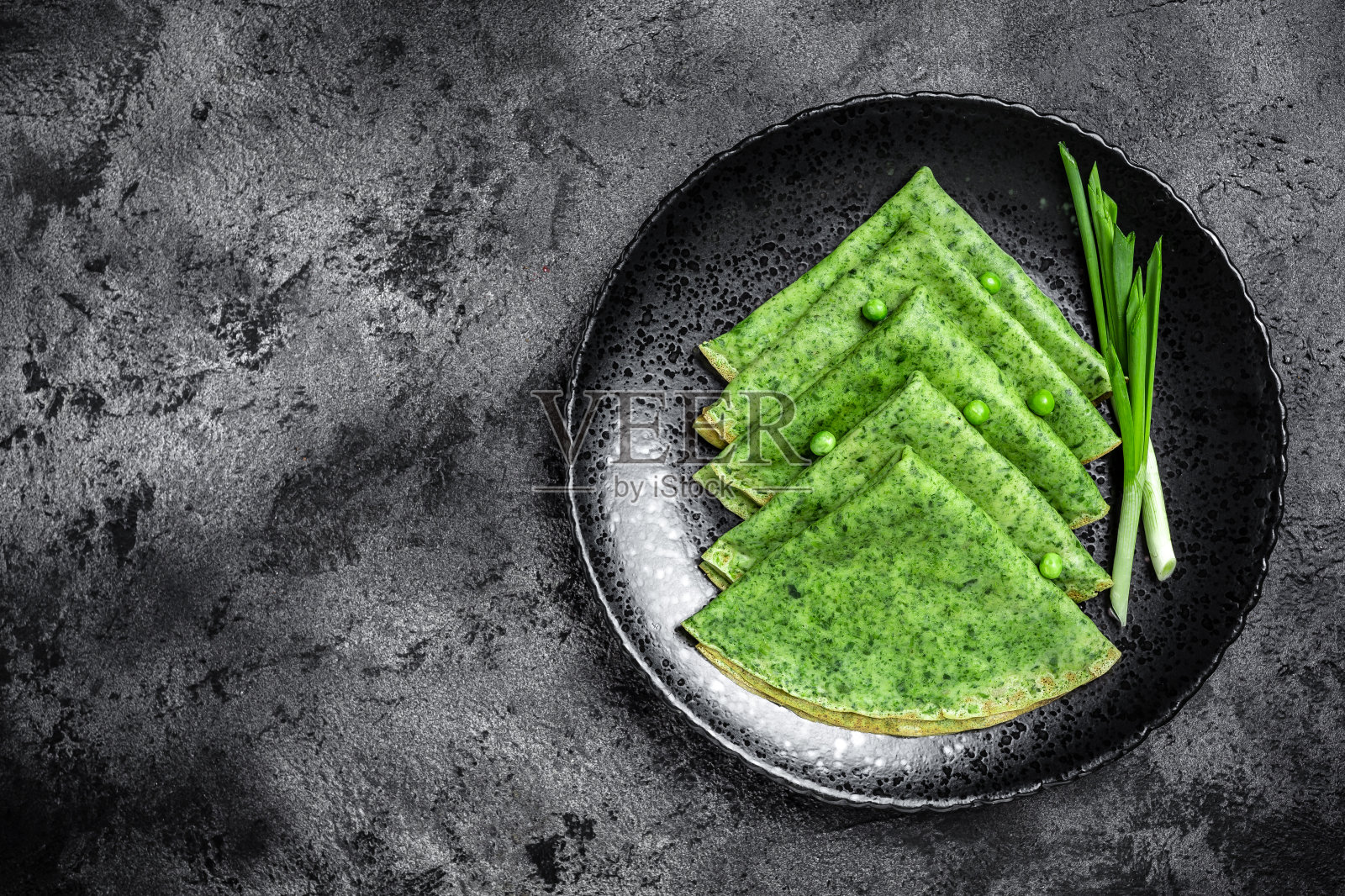 菠菜绿煎饼薄饼在深色的背景。美味的健康的早餐。素食，俯视图照片摄影图片