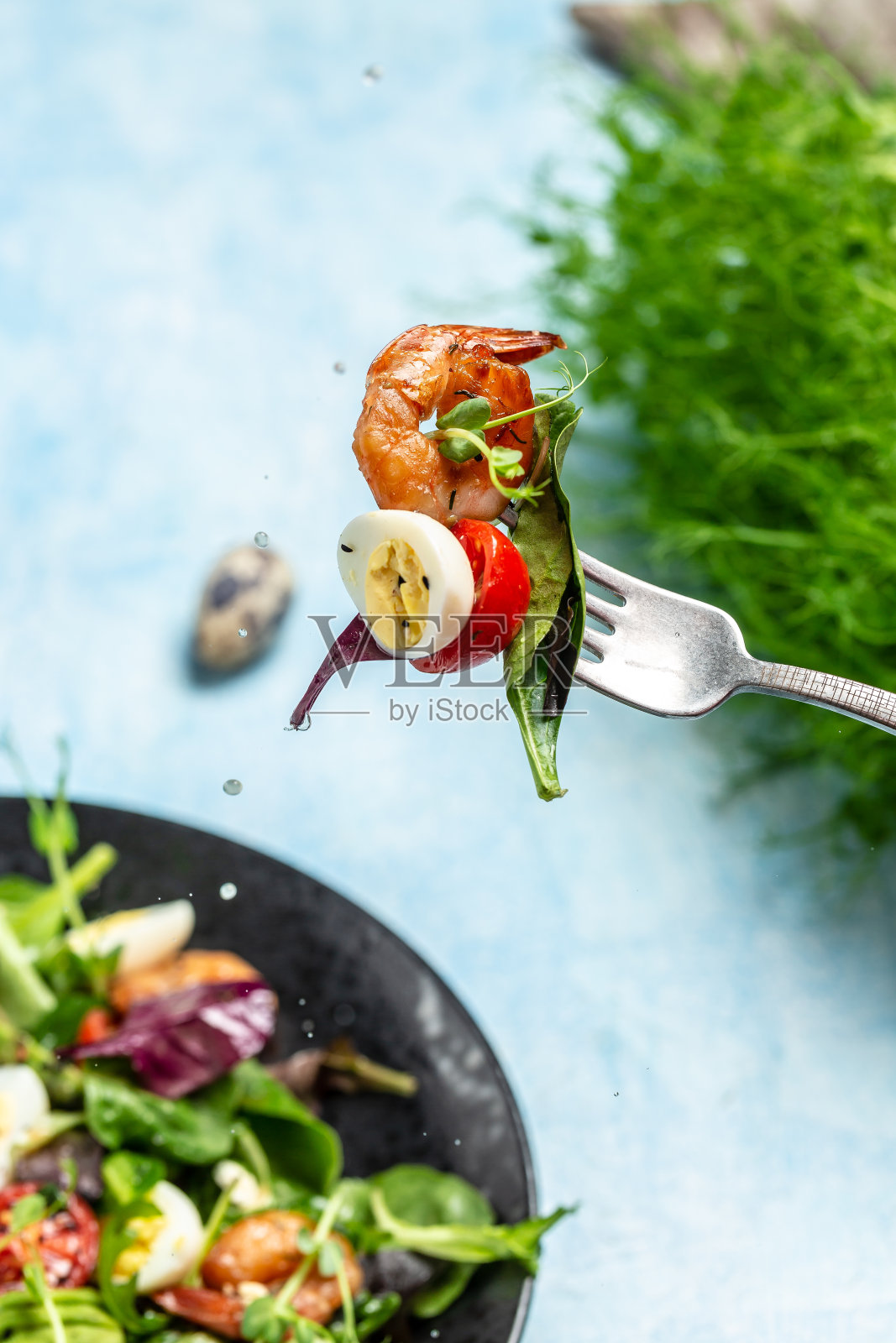 用叉子搭配蔬菜沙拉，樱桃番茄，黄瓜，鳄梨，鸡蛋和熏虾。洒点柠檬汁，干净的饮食。食品配方的背景。近距离照片摄影图片