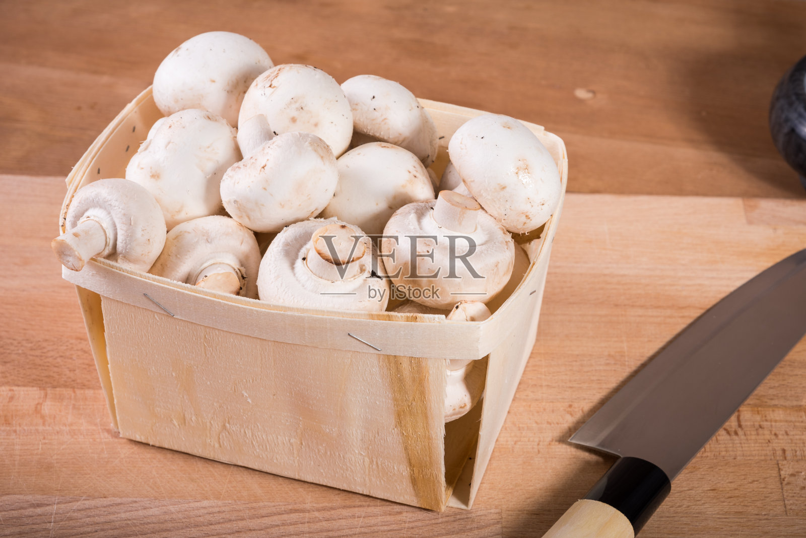 篮子里放着白色的冠军，桌子上放着一把刀，俯视图，特写照片摄影图片