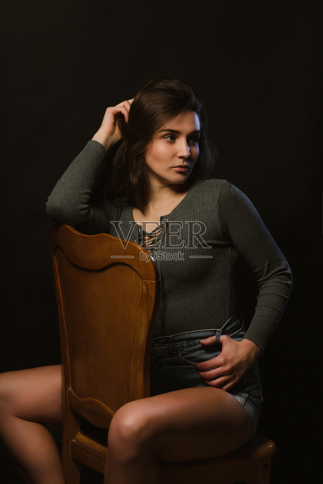 时尚的黑发女孩坐在演播室模特测试期间，穿着灰色内衣和牛仔裤短裤照片摄影图片