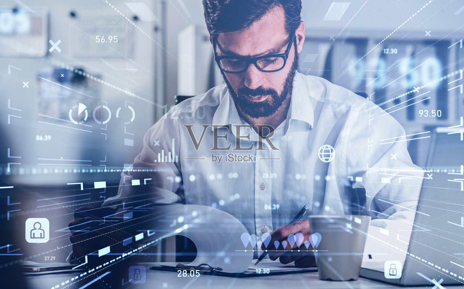 英俊的商人正坐在工作场所的笔记本电脑前，做着笔记分析饼状图和图表。营销分析的概念。数字接口与物流照片摄影图片