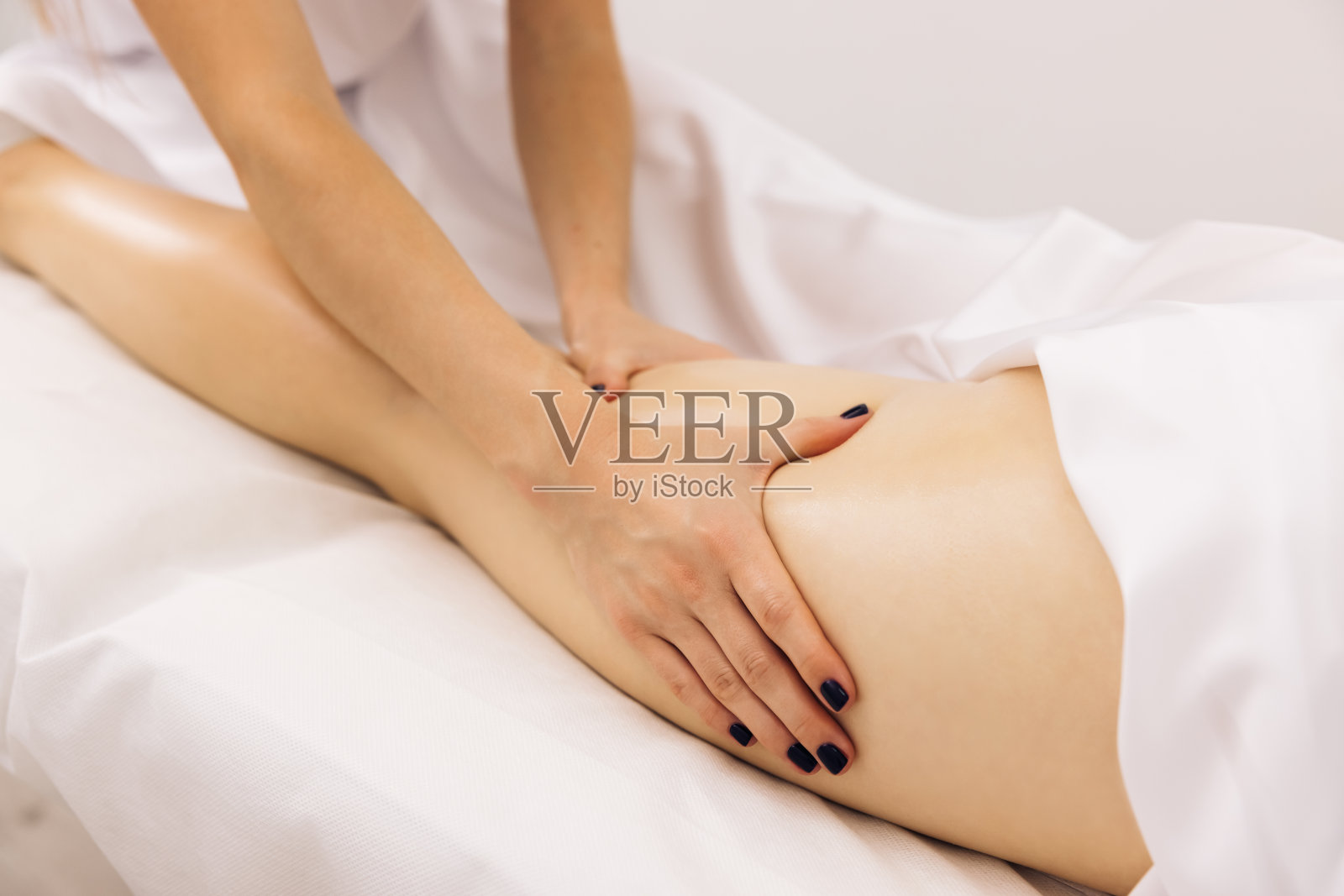 美容院里，按摩师正在给躺着的女人做背部按摩。专业的按摩和触摸女性客户的皮肤，使用传统的技术。专家工作与病人的身体照片摄影图片