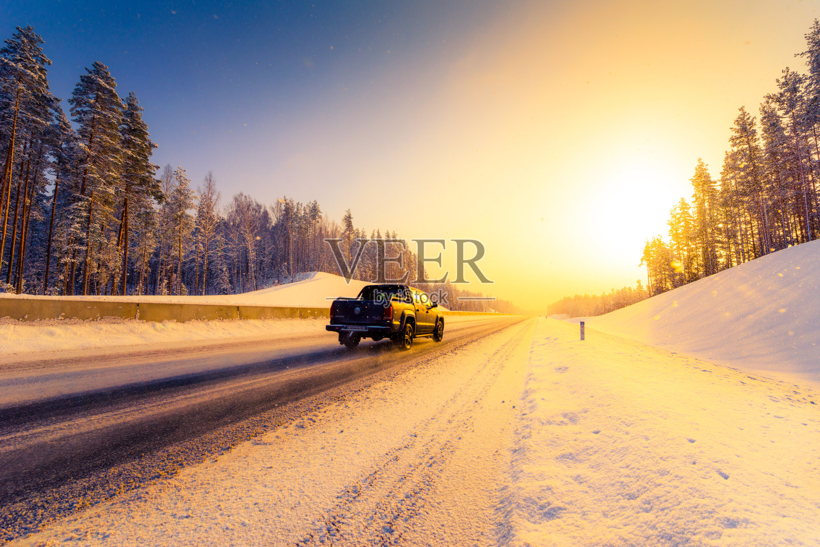 日出在一个晴朗的冬日早晨，皮卡车在高速公路上的雪。从路边看过去。针叶林。照片摄影图片