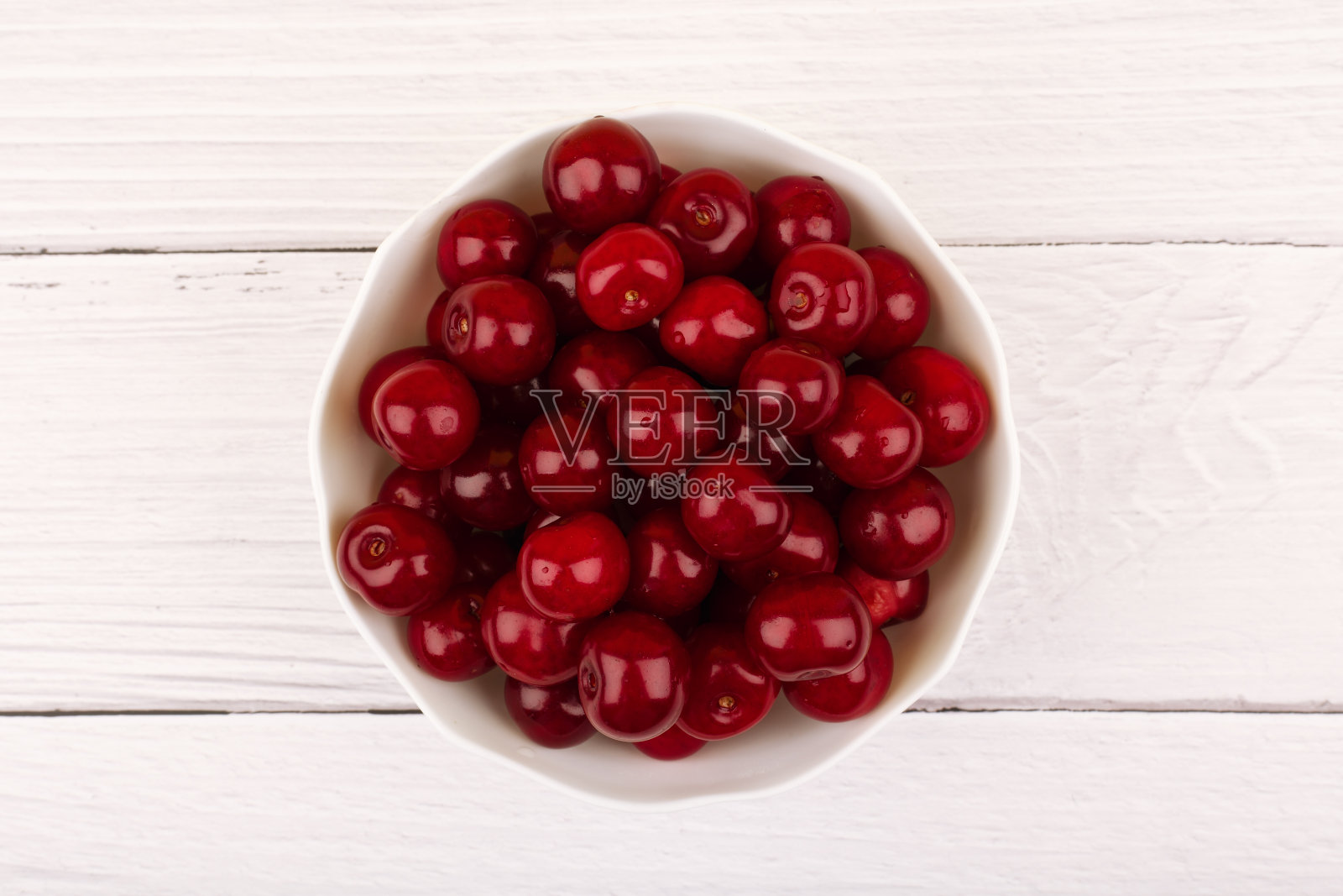 俯视图的成熟甜樱桃在白色碗上白色木桌照片摄影图片
