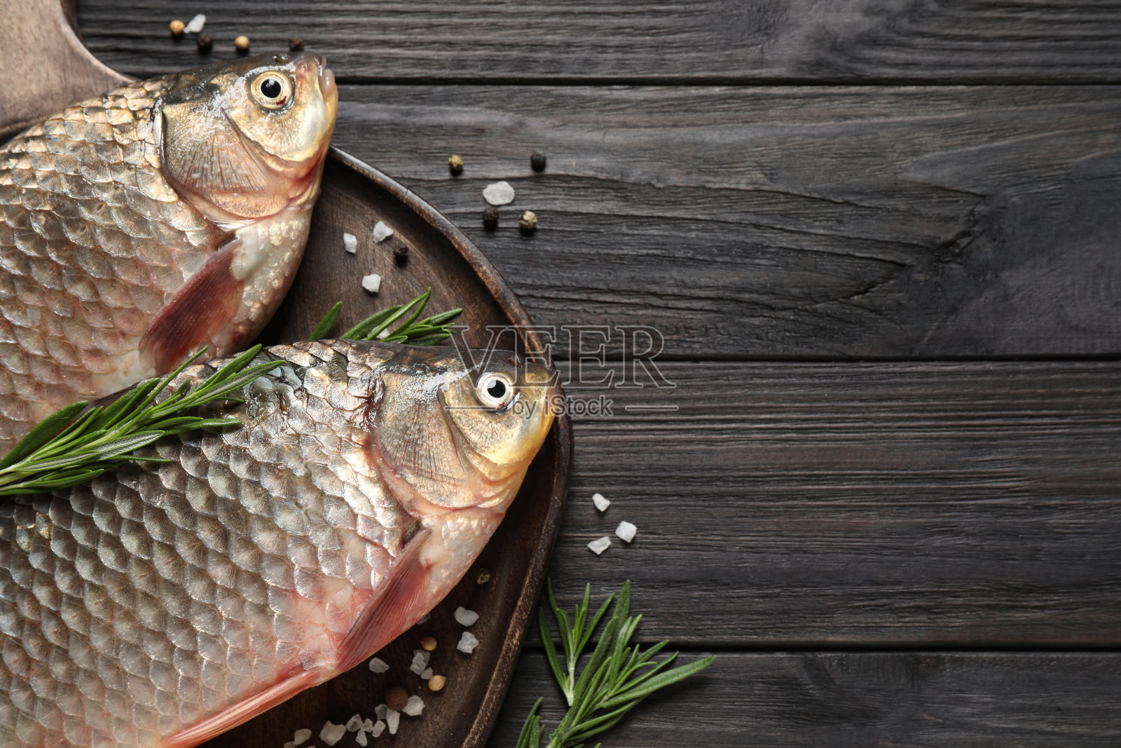 新鲜的生鲫鱼和配料放在黑色木桌上，上面有文字空间。河里的鱼照片摄影图片