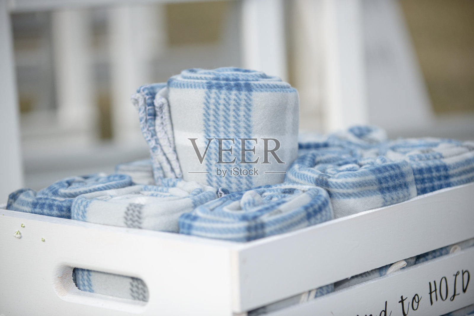 婚礼上的白色板条箱上写着“To have and To hold in case you get cold”，上面还有卷好的宾客毛毯照片摄影图片