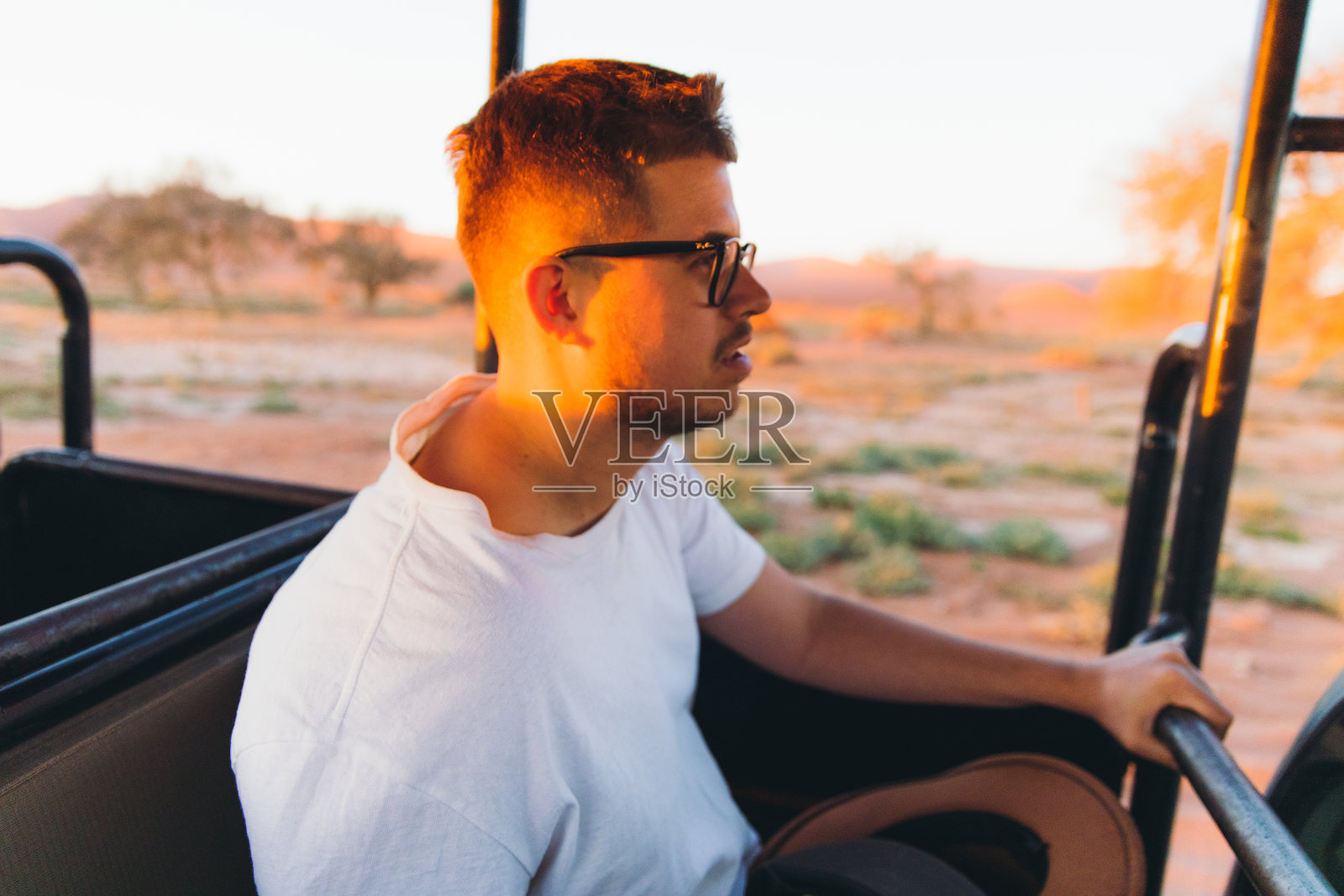在纳米比亚索苏瓦莱的明亮的夕阳下，一名男子在沙丘上驾车照片摄影图片