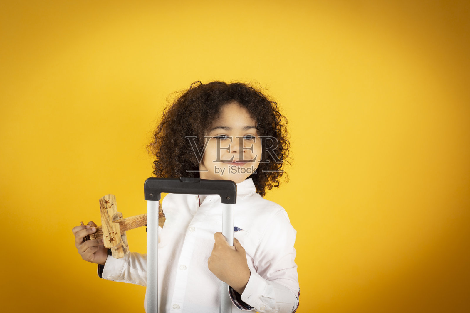 男孩带着一个手提箱和一个黄色背景的玩具飞机，旅行的概念照片摄影图片