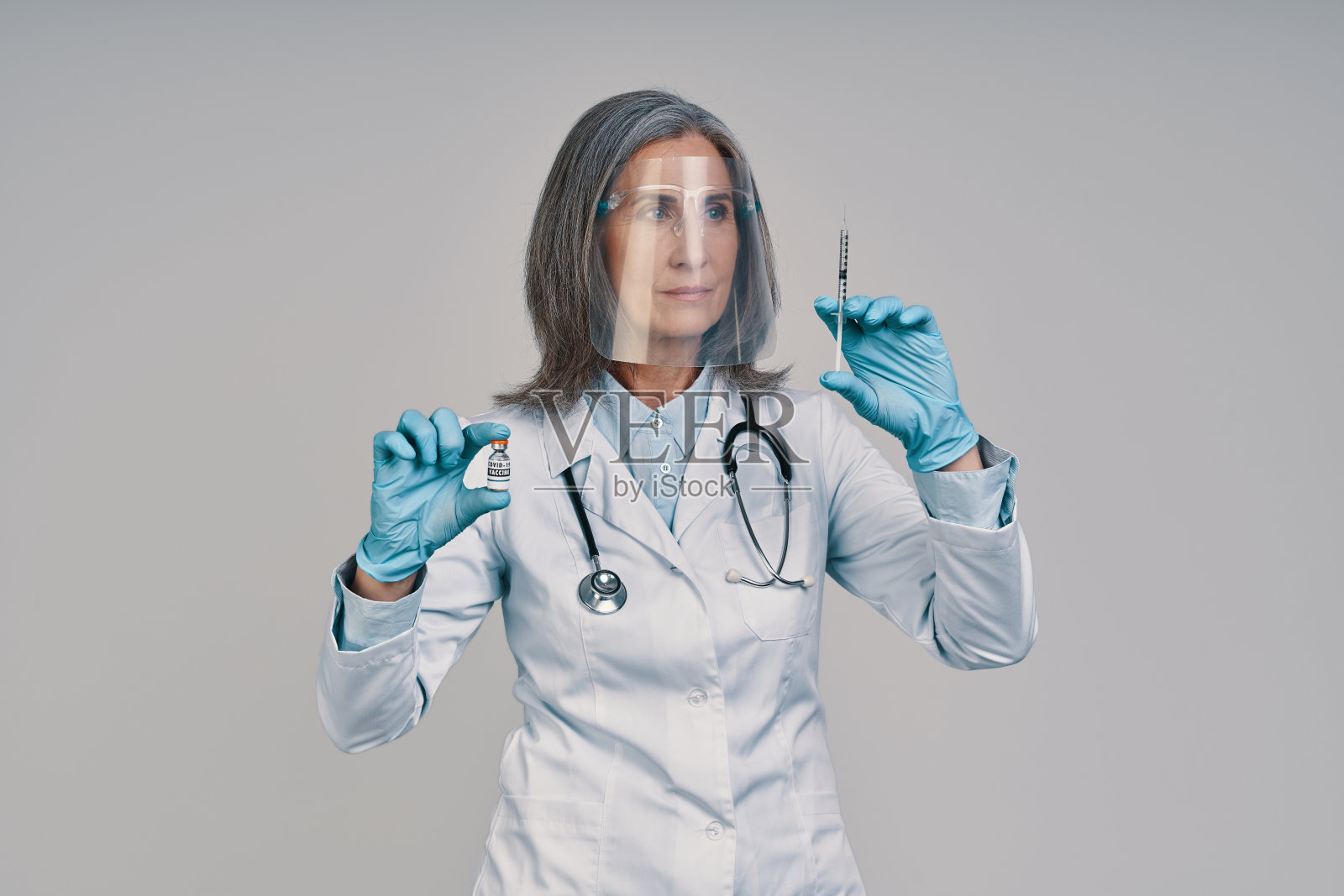 成熟美丽的女医生在面罩拿着注射器照片摄影图片