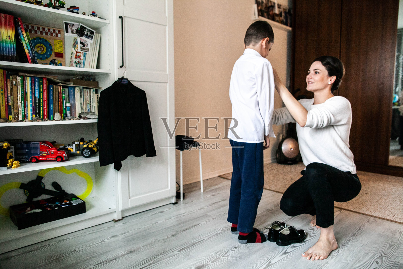 母亲给儿子穿衣服去上学照片摄影图片