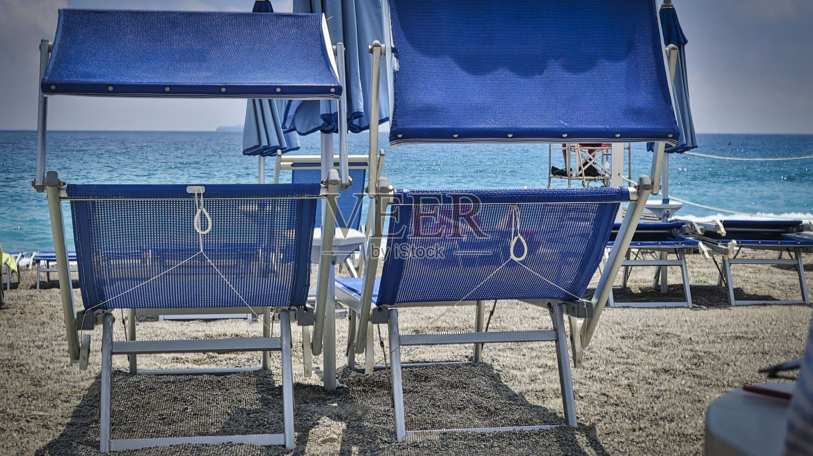 两把蓝色的躺椅放在意大利海滩的沙滩上照片摄影图片