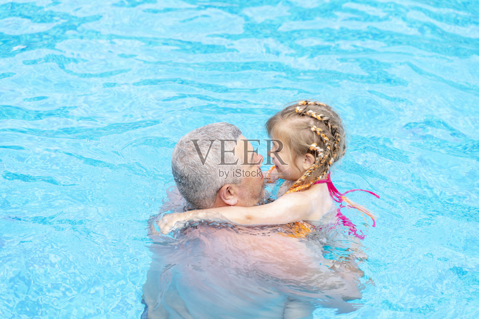 爸爸和小女儿暑假在游泳池里游泳照片摄影图片