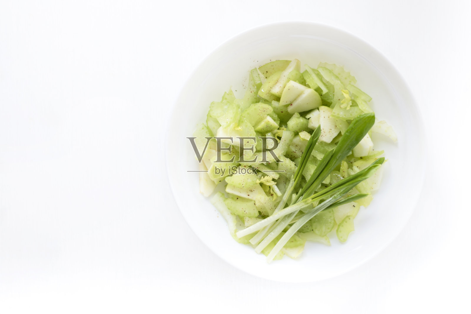 春季维生素沙拉，芹菜，苹果和绿色蔬菜在一个白色的盘子，俯视图照片摄影图片