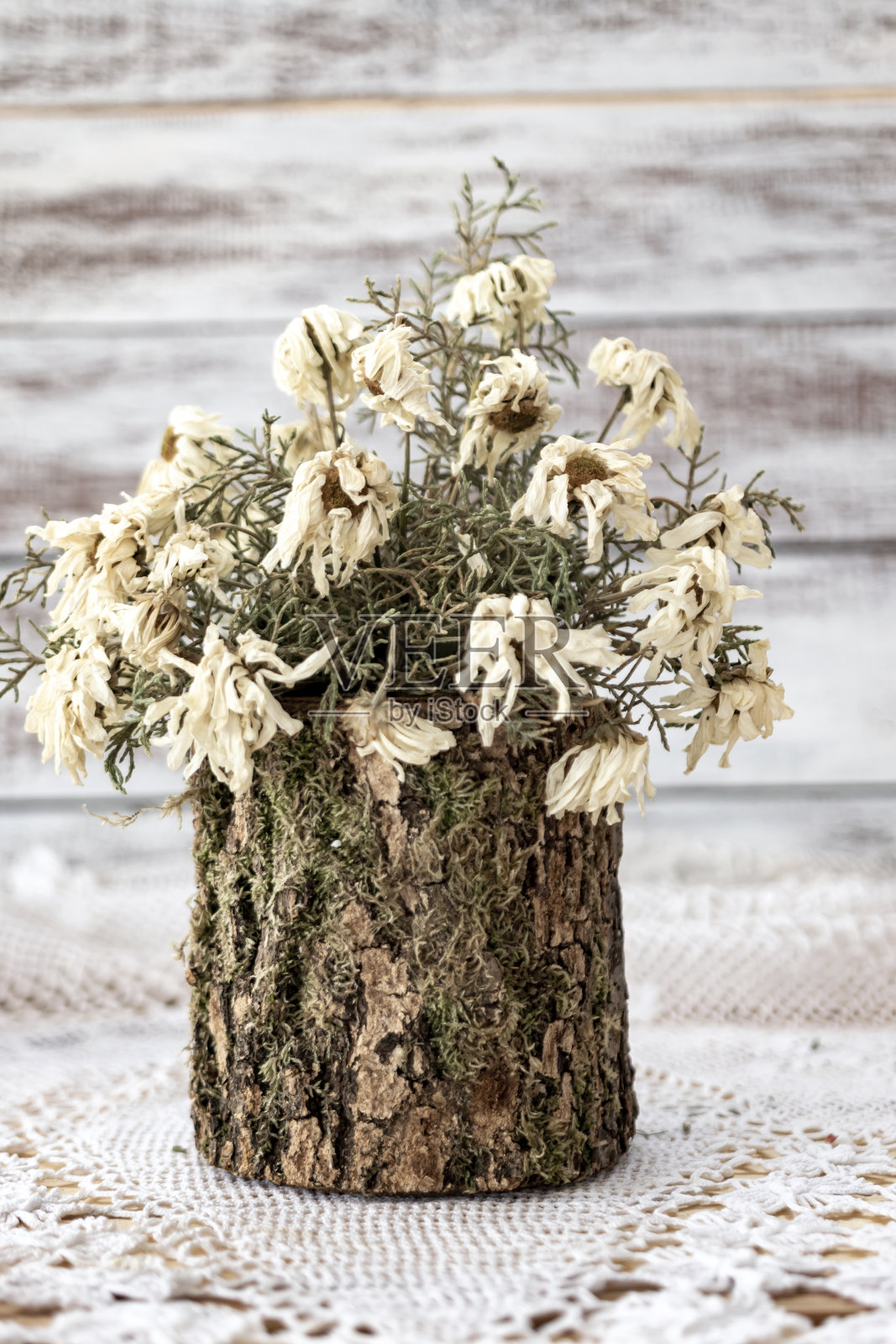 花边手工编织，桌布。在一张粉刷成白色的木桌上。上面有一个铜杯，里面装着干花。复古的照片。照片摄影图片