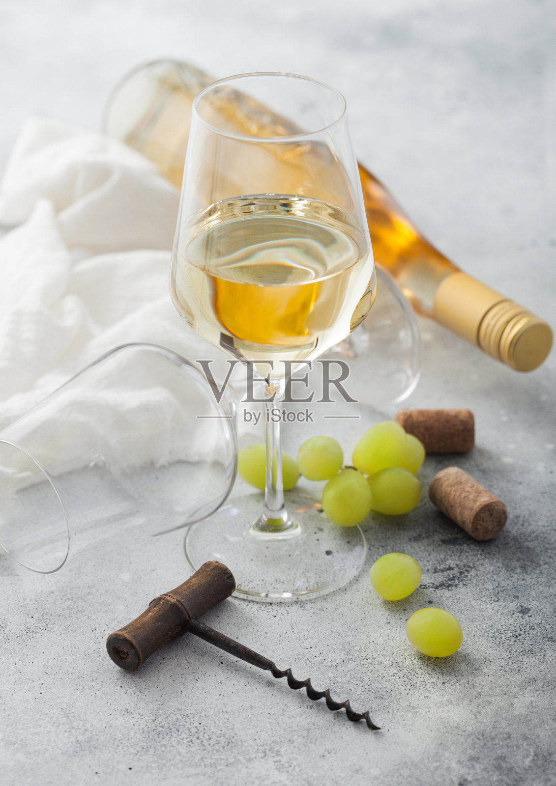 一杯清爽的白葡萄酒，葡萄，螺旋和瓶子在光线的背景。照片摄影图片