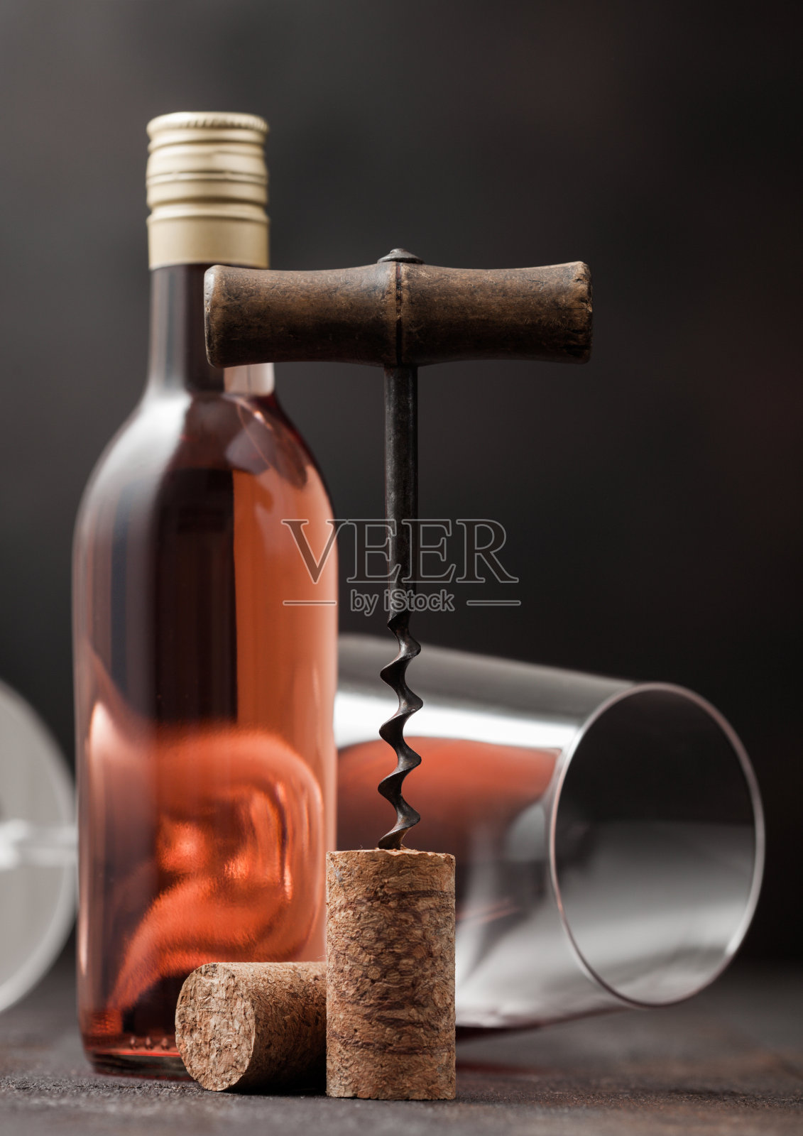 一瓶粉红玫瑰葡萄酒与玻璃和古董开瓶器和软木板。照片摄影图片