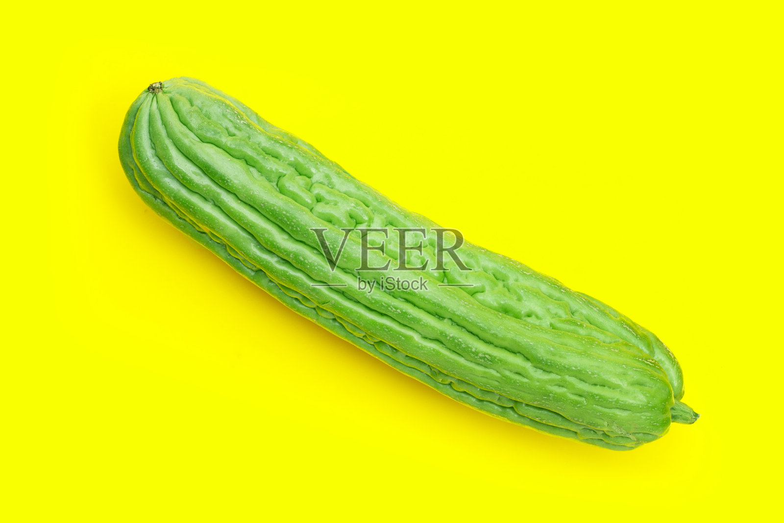 黄色背景上的苦瓜。照片摄影图片