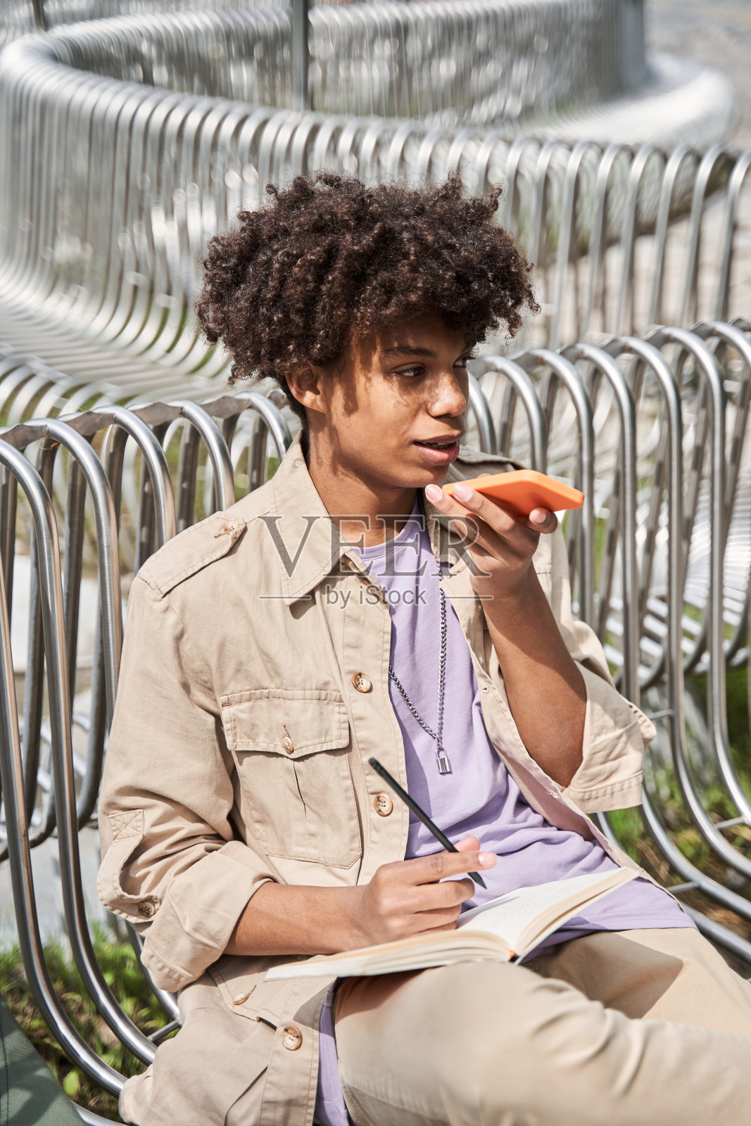 一名男子戴着无线耳机坐在长椅上和同伴聊天照片摄影图片