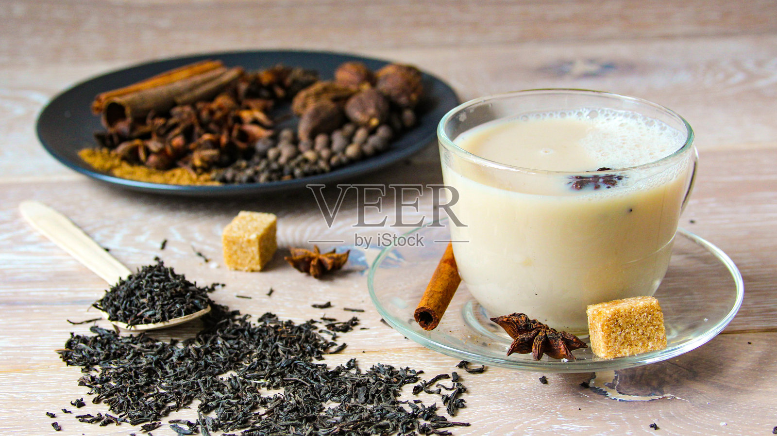 传统印度饮料-香料马沙拉茶木制背景。关闭印度或亚洲流行的传统饮料香料和糖。在玻璃杯中加入不同成分的香料茶。照片摄影图片