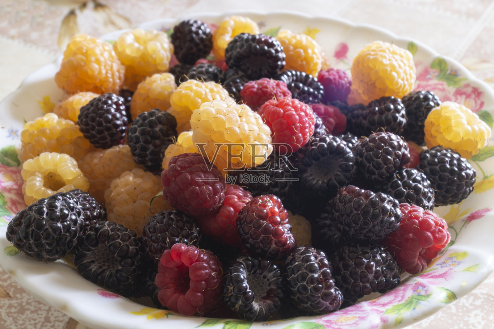 黑色和红色的覆盆子放在桌子上的一个盘子里照片摄影图片