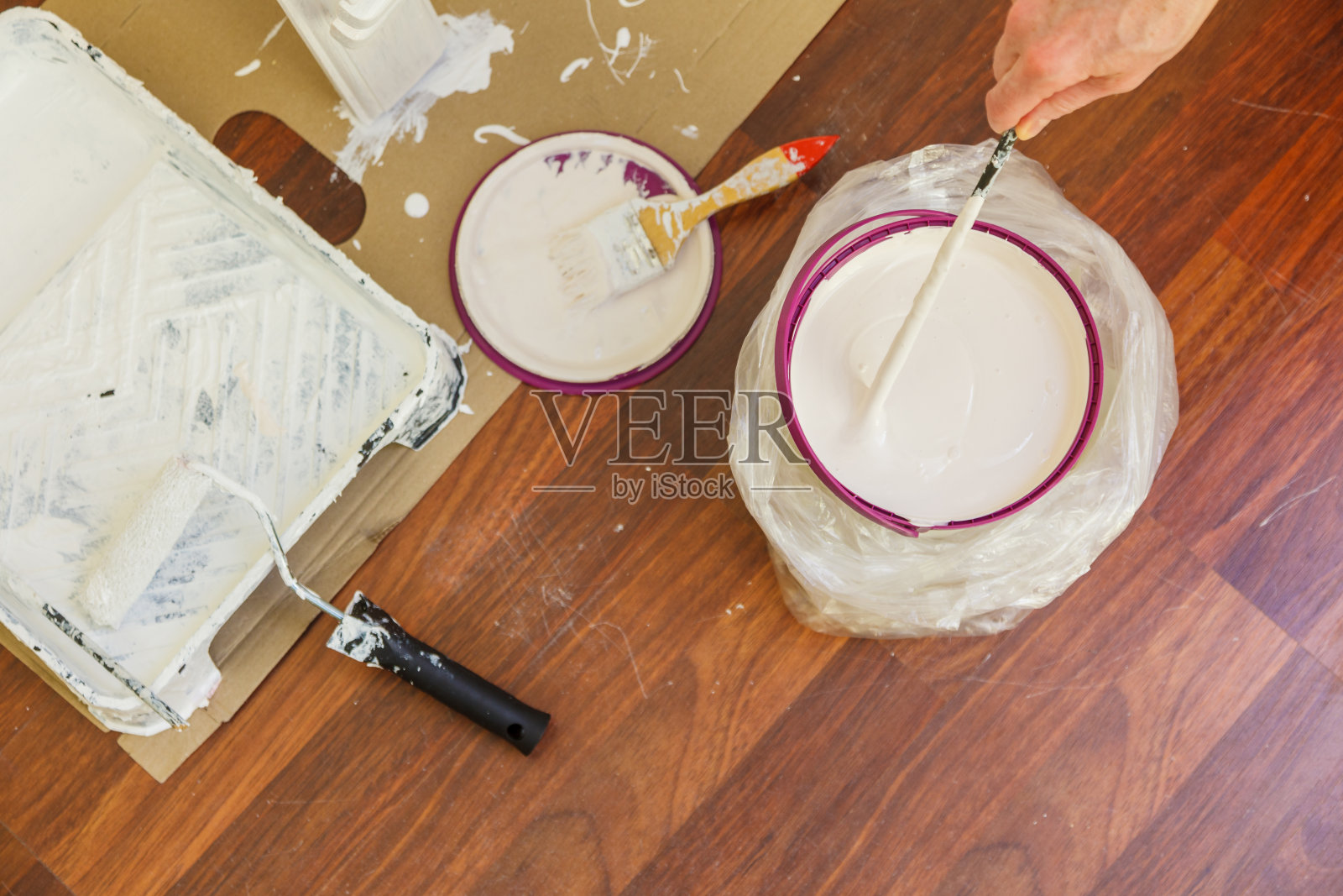 有人在桶里搅拌白漆。照片摄影图片