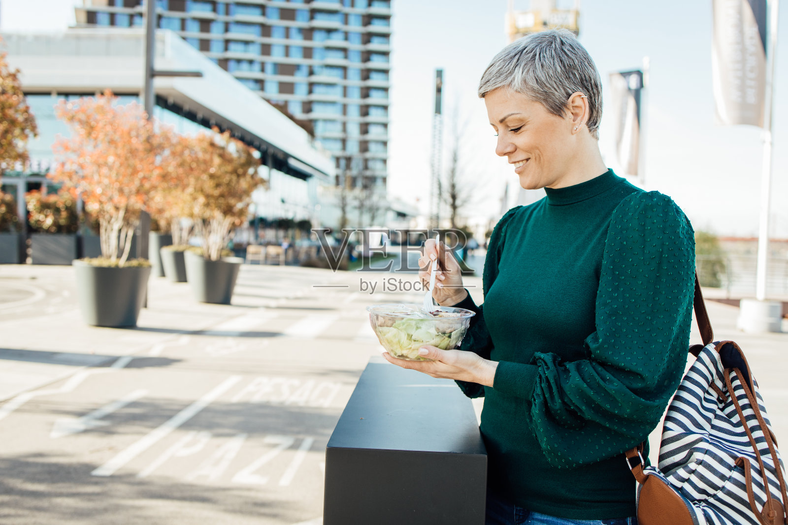 度假的女人在城市里吃着塑料盒子里的午餐照片摄影图片