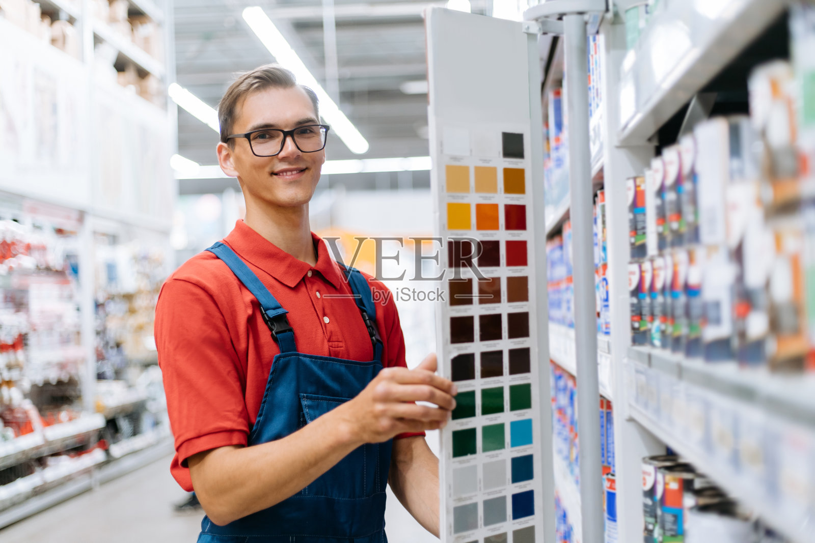 微笑的建筑商店店员站在调色板样品附近照片摄影图片