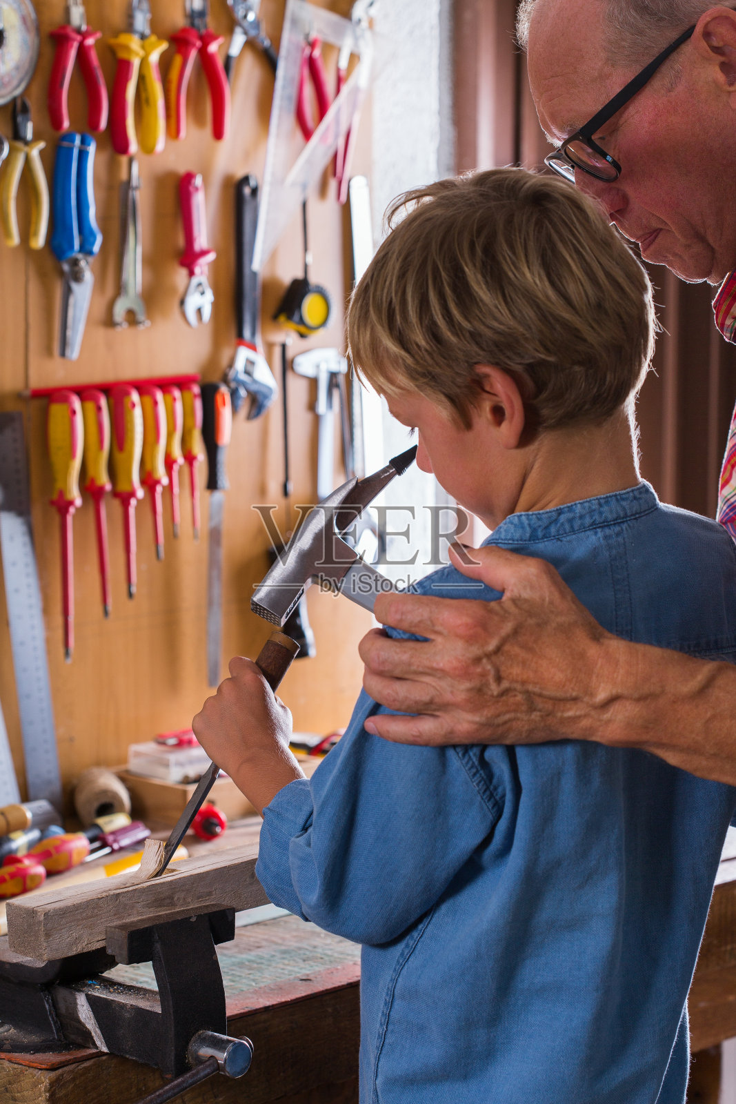 祖父教男孩用细木工工具在长凳上干活照片摄影图片