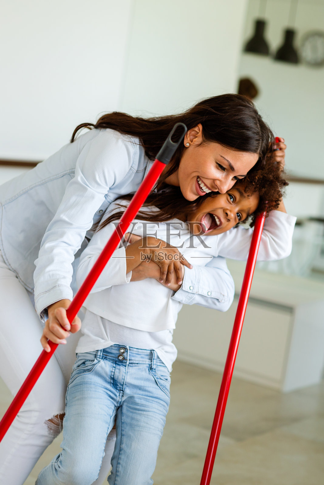 多民族家庭快乐地打扫房子，玩得开心。孩子们帮妈妈收拾房间。照片摄影图片