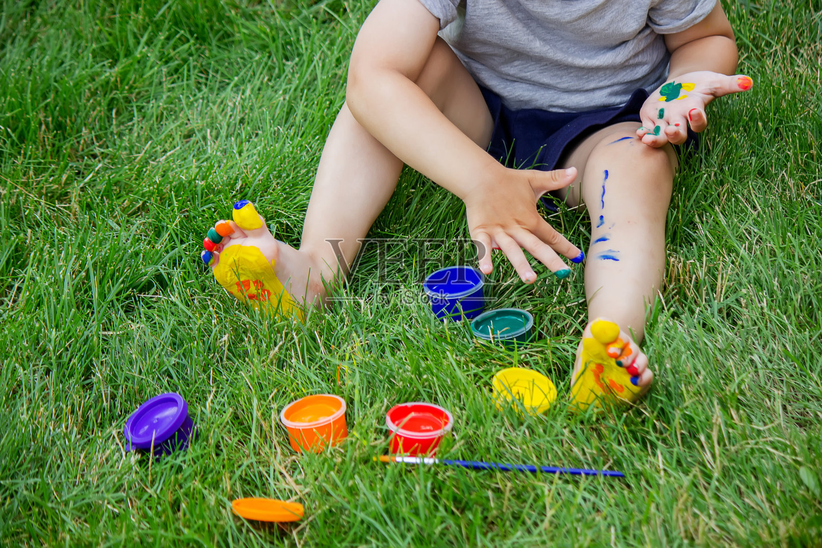 孩子在腿上画了一个图案。一幅有趣的画，身上有鲜艳的颜色。照片摄影图片