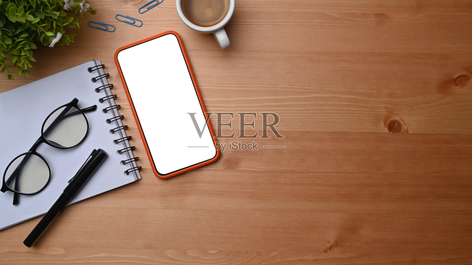 俯视图智能手机，咖啡杯和笔记本在木桌上。照片摄影图片
