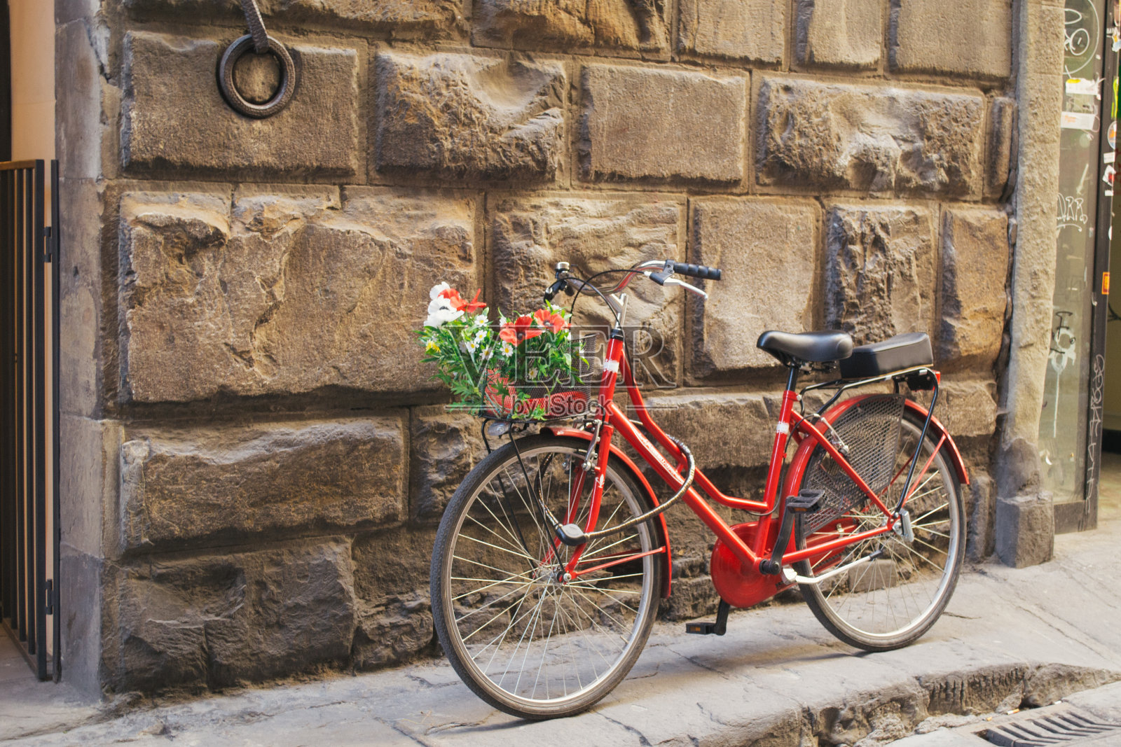 在佛罗伦萨市中心的人行道上，一辆带花篮的红色旧自行车照片摄影图片