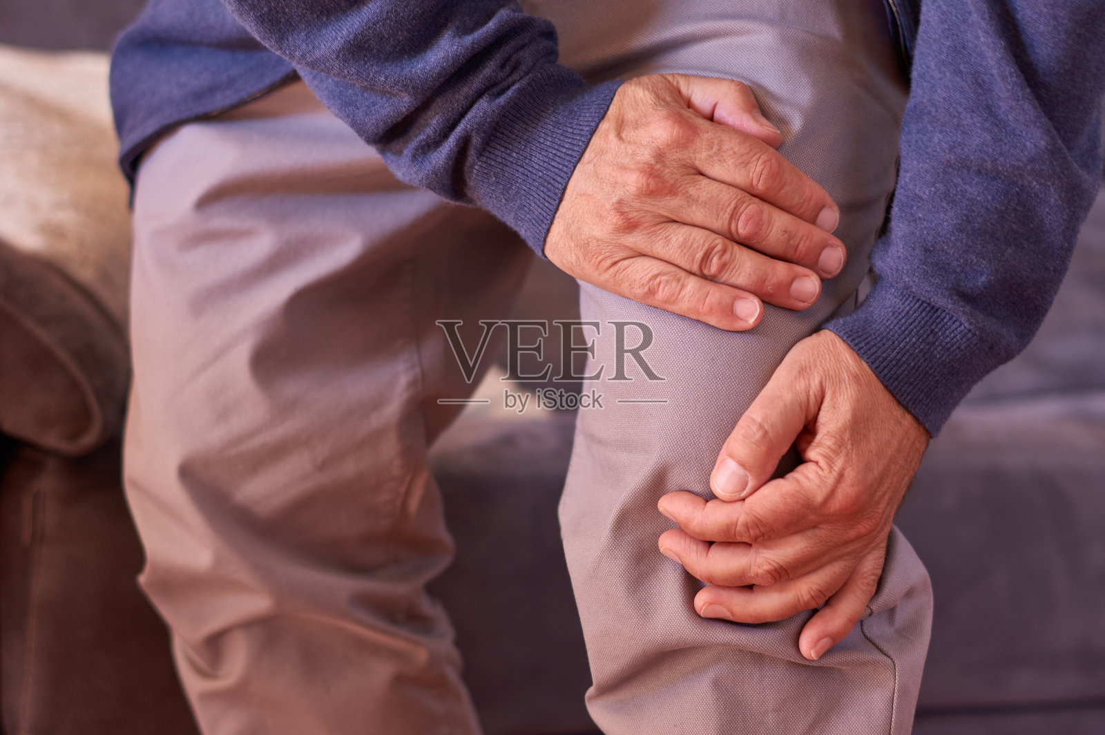 一名中年白人男子因疼痛而用手托着膝盖照片摄影图片