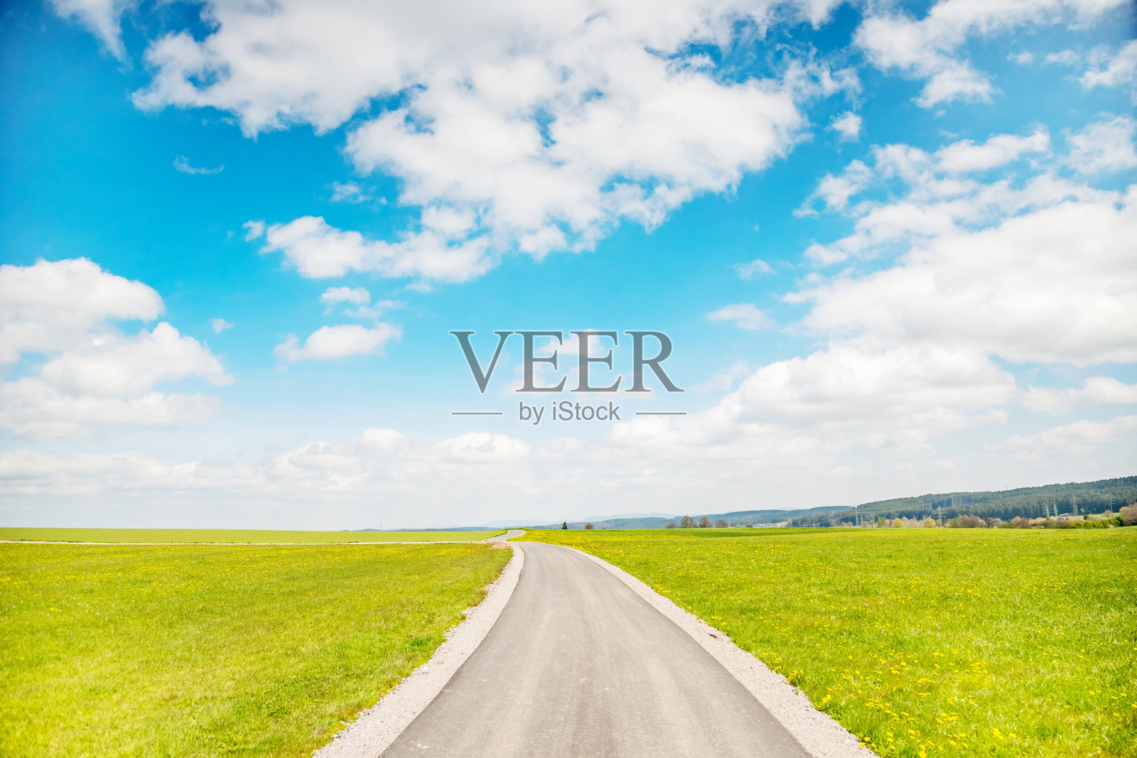 蓝天白云下的乡间小路;路的两边鲜花盛开。全景照片摄影图片